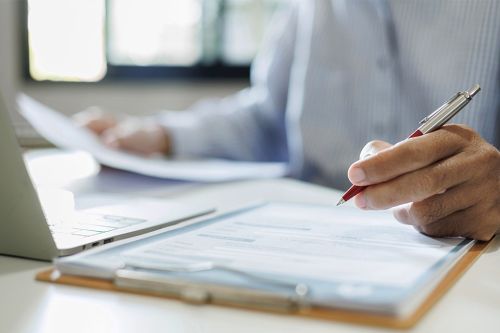 Person mit Dokumenten und Laptop